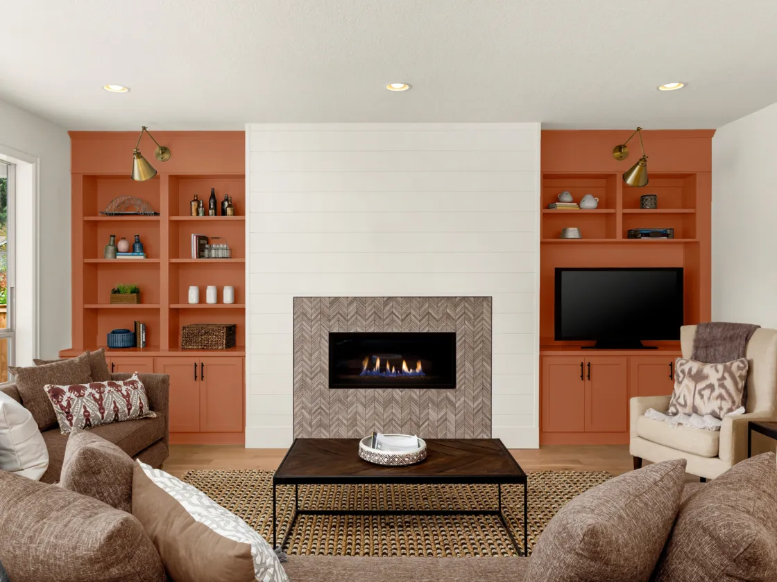 A cozy, inviting living room with brown couches, fireplace and terracotta accent elements